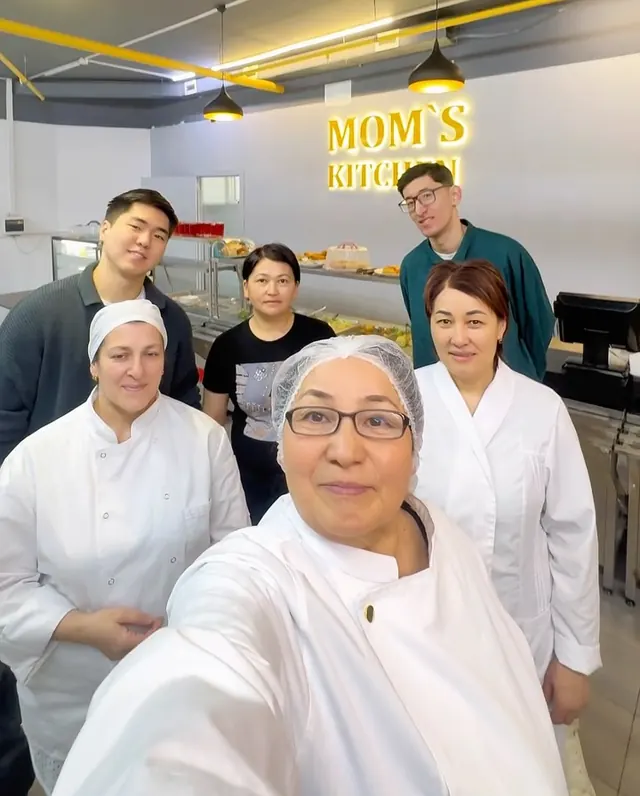 Шеф-повар Mom’s Kitchen в очках и её команда в зале столовой